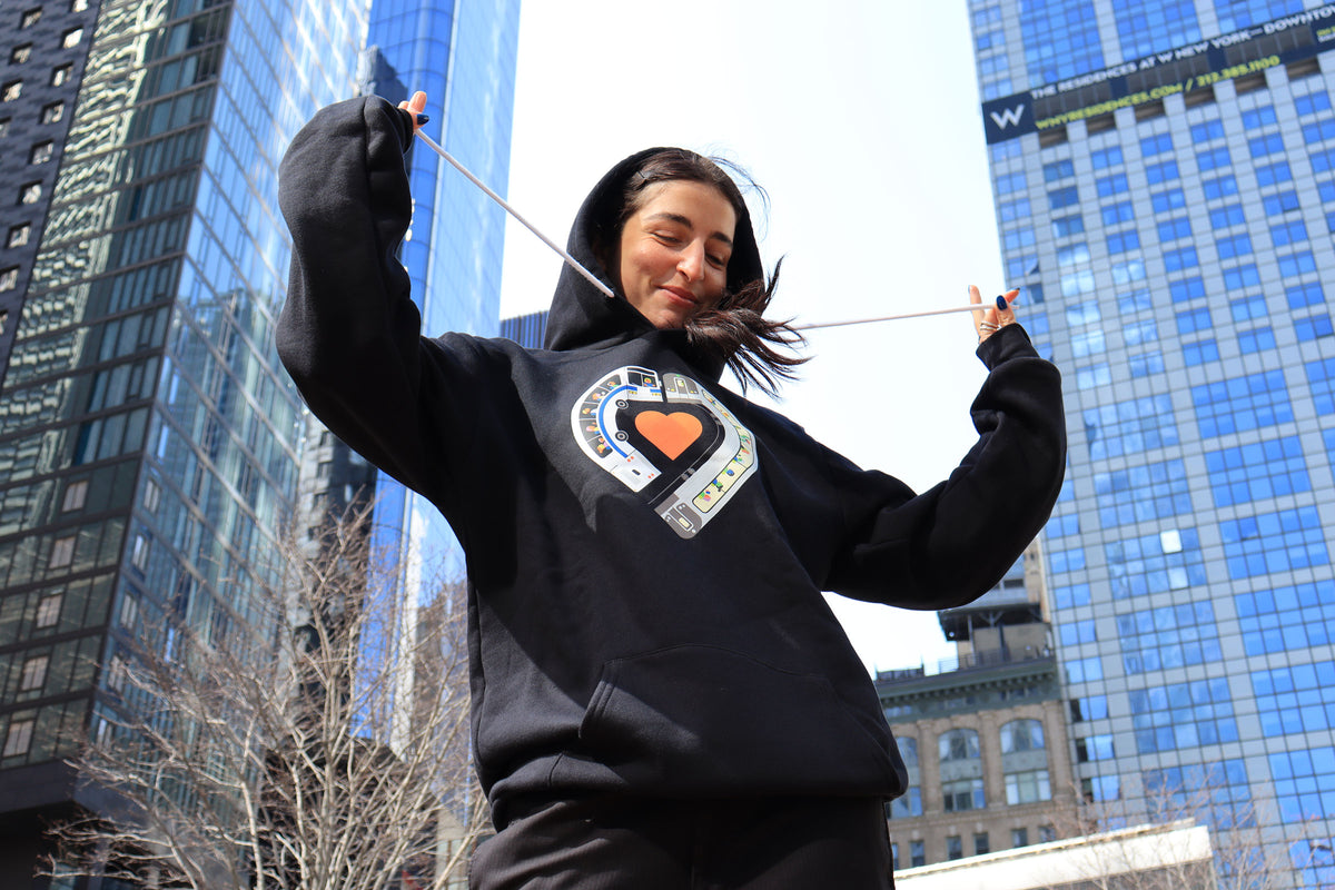 Woman wearing Riders Alliance hoodie in front of sky scrapers.